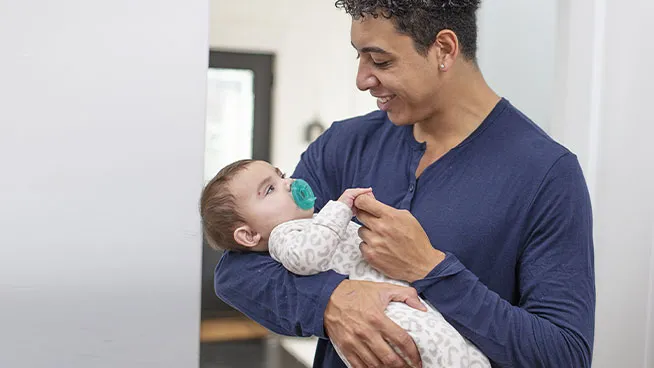 Dad cradling baby and holding baby's hand