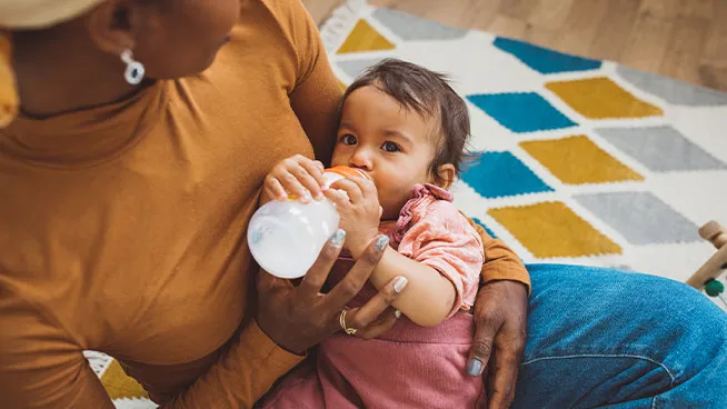 Mom cradling baby and feeding her a bottle