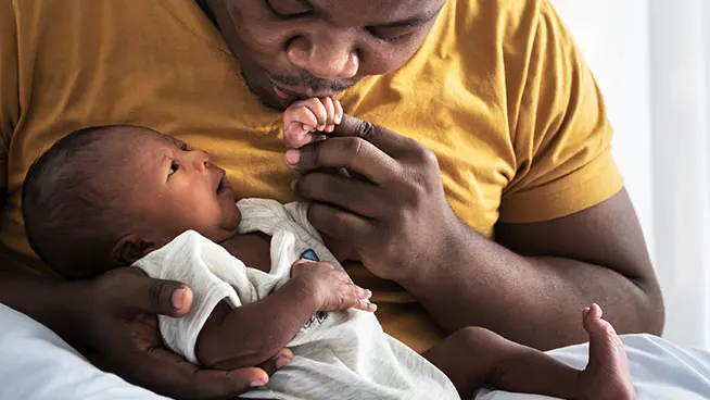 Father kissing the hand of a premature baby.