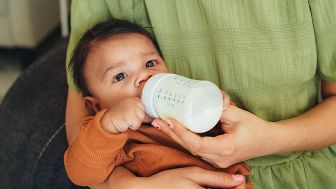 Baby drinking bottle in mother's arms