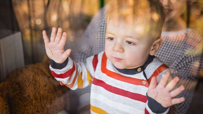 Bebé mirando por la ventana después de que sus padres se fueron